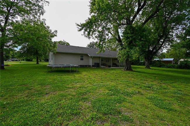 Back of property with a trampoline, a yard, and cooling unit | Image 43