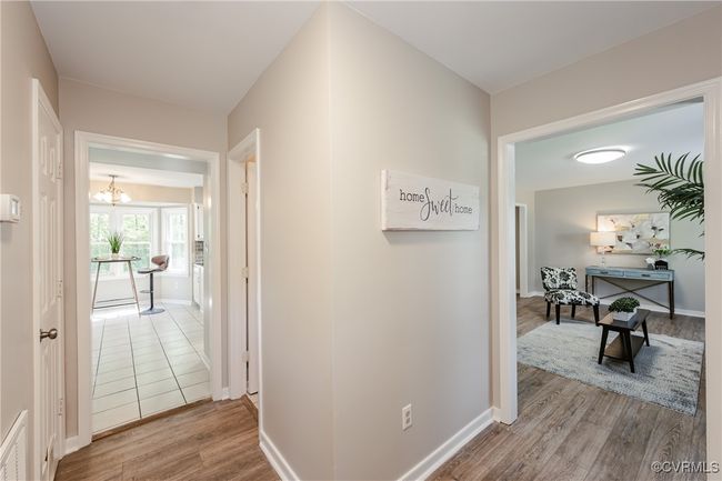 Corridor with baseboards, wood finished floors, and a chandelier | Image 4