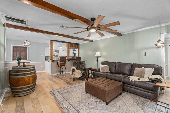 The room is accented with exposed wood beams, opening up to the dining and kitchen area, creating a charming and comfortable atmosphere. | Image 18
