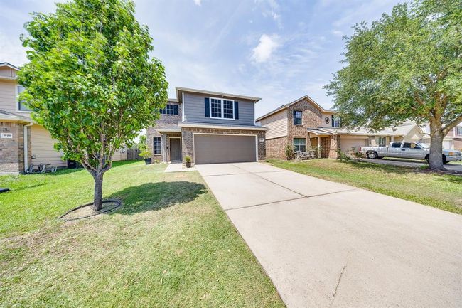 Front yard features a beautiful mature tree, adding natural charm and shade to the landscaped entrance. | Image 7