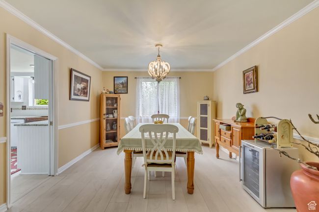 Dining space with baseboards, crown molding, a chandelier, and light wood-style flooring | Image 18