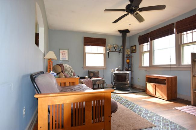 Bedroom featuring a ceiling fan, wood finished floors, baseboards, and a wood stove | Image 8