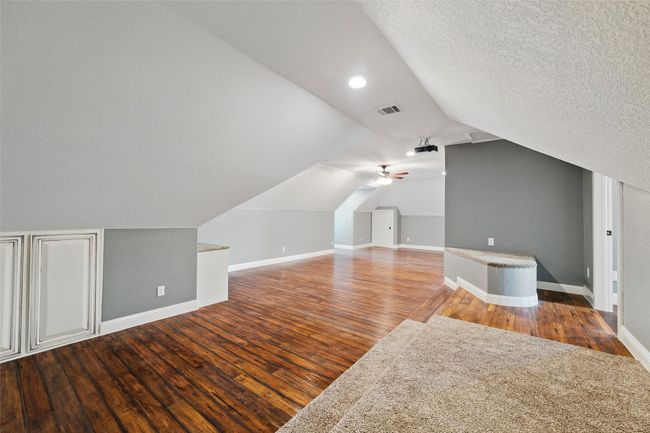 Bonus room with wood finished floors, baseboards, vaulted ceiling, a textured ceiling, and ceiling fan | Image 23
