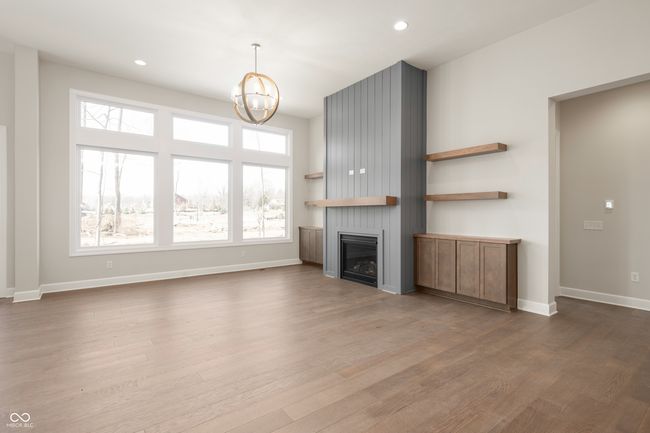 Family room featuring wood finished floors, decorative shelving and cabinetry plus large windows offering an abundance of natural light. | Image 12