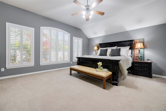 primary bedroom featuring lofted ceiling, ceiling fan, view of the yard, and lots of space. | Image 11