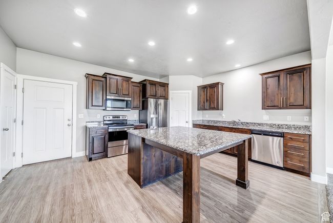 Kitchen with light wood-style floors, stainless steel appliances, dark brown cabinets, and recessed lighting | Image 7
