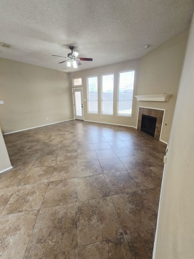 Unfurnished living room with a textured ceiling, a tile fireplace, a ceiling fan, and baseboards | Image 14