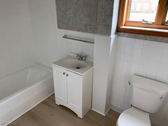 Bathroom with hardwood / wood-style floors, vanity, and tile walls | Image 11