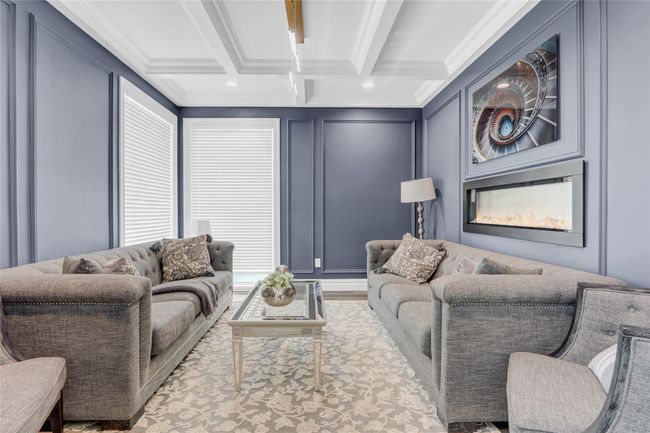Living area with a decorative wall, beam ceiling, ornamental molding, and coffered ceiling | Image 4