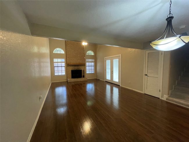 Unfurnished living room with dark wood-style flooring, baseboards, a fireplace, and stairs | Image 11