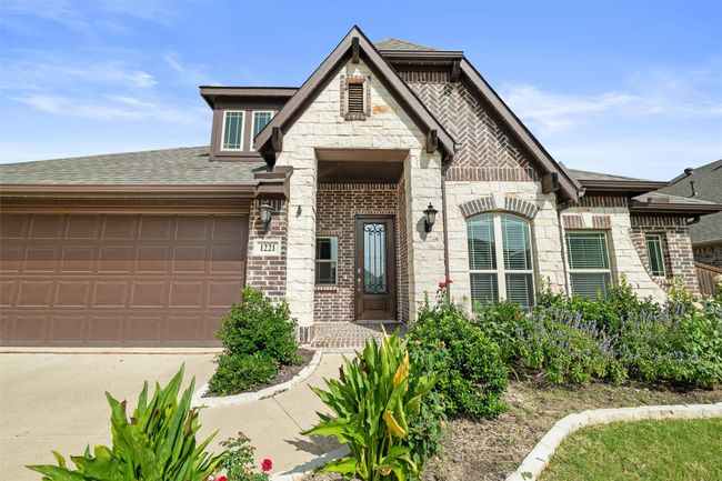 French provincial home with stone siding, roof with shingles, a garage, brick siding, and driveway | Image 5