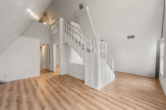 Unfurnished living room featuring stairway, high vaulted ceiling, and laminate floors | Image 21