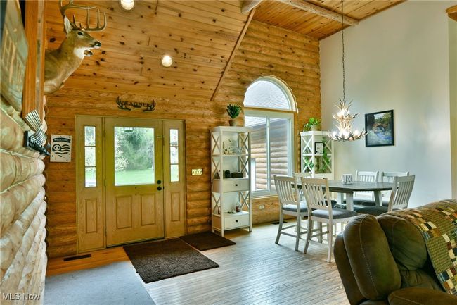 Entrance foyer with rustic walls, a chandelier, plenty of natural light, hardwood / wood-style flooring, and high vaulted ceiling | Image 6