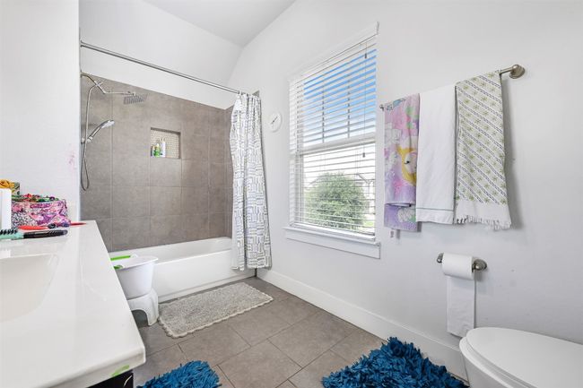 Bathroom featuring tile patterned flooring, healthy amount of natural light, shower / bath combo with shower curtain, and vanity | Image 14