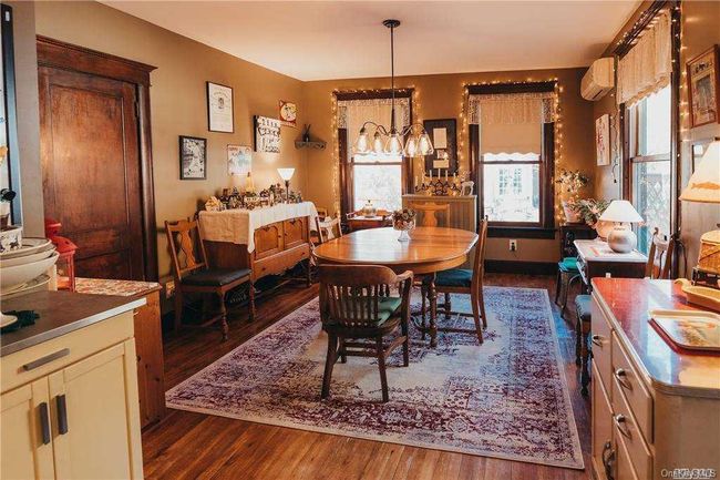 Dining area with a chandelier, dark wood-style flooring, and a wall mounted air conditioner | Image 38