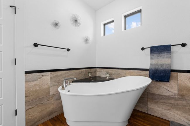 Full bath with tile walls, wood finished floors, a wainscoted wall, and a soaking tub | Image 22