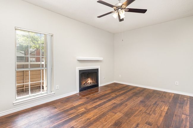 Unfurnished living room with a fireplace with flush hearth, wood finished floors, and ceiling fan | Image 4