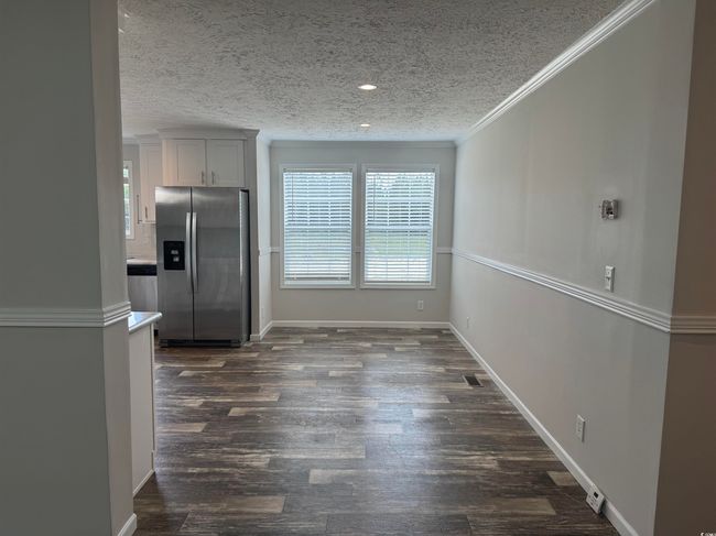 Unfurnished dining area with a textured ceiling, dark wood finished floors, crown molding, and recessed lighting | Image 15