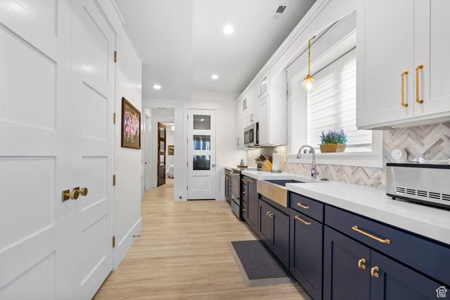 Kitchen featuring a sink, white cabinets, decorative backsplash, and stainless steel appliances | Image 71
