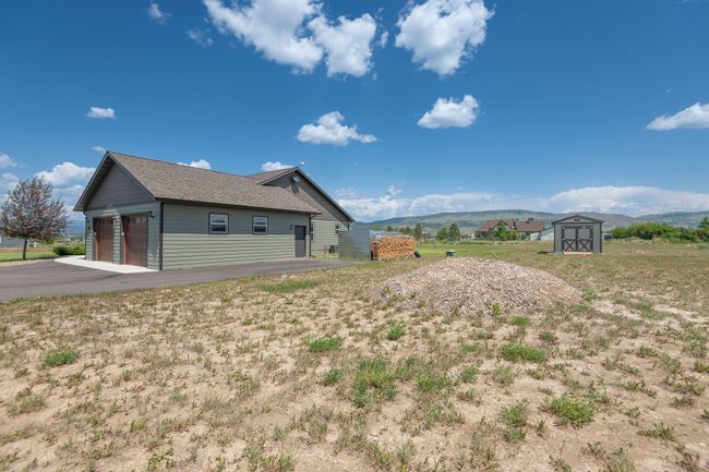 View of side of home with a storage unit, a mountain view, and roof with shingles | Image 29