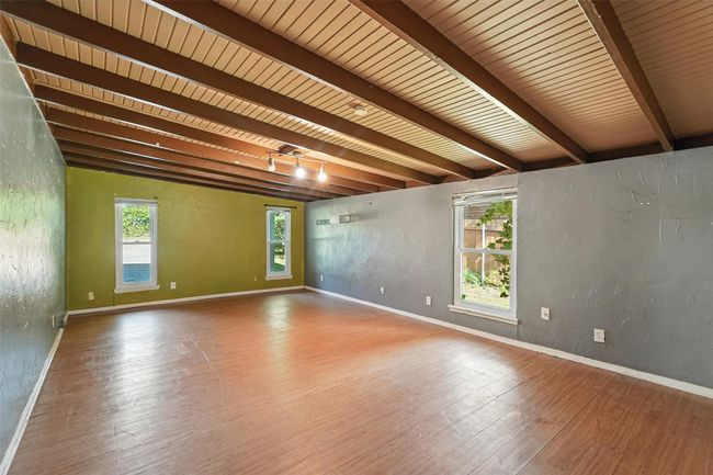 Spare room featuring wood finished floors, a textured wall, and a wood ceiling with exposed beams | Image 21