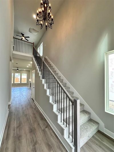 Staircase with a high ceiling, wood-type flooring, and ceiling fan with notable chandelier | Image 3