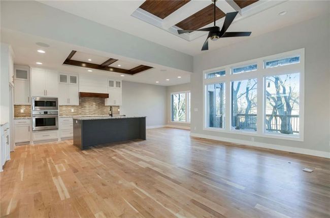 Kitchen with appliances with stainless steel finishes, beam ceiling, decorative backsplash, white cabinetry, and light wood-style floors | Image 6