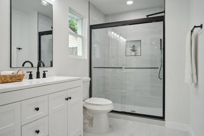 Bathroom featuring baseboards, toilet, a stall shower, and vanity | Image 16