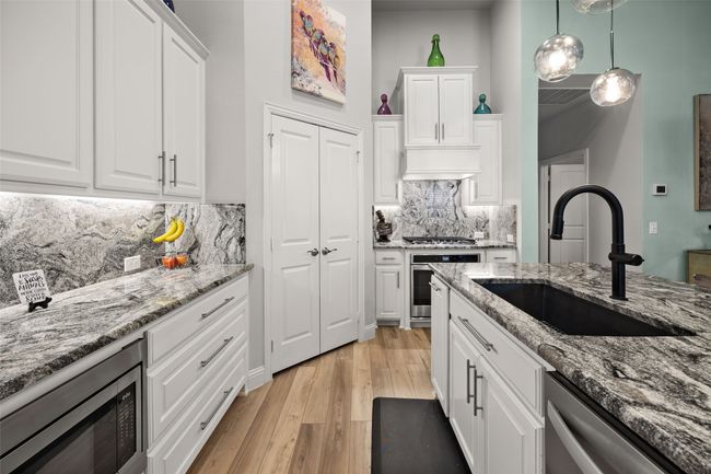 Kitchen with a sink, stainless steel appliances, light wood-style flooring, white cabinetry, and tasteful backsplash | Image 8