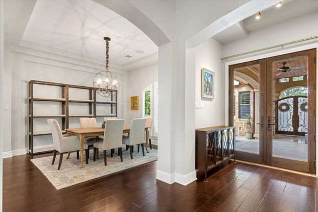 Dining room featuring arched walkways, a chandelier, baseboards, and dark wood-style flooring | Image 4