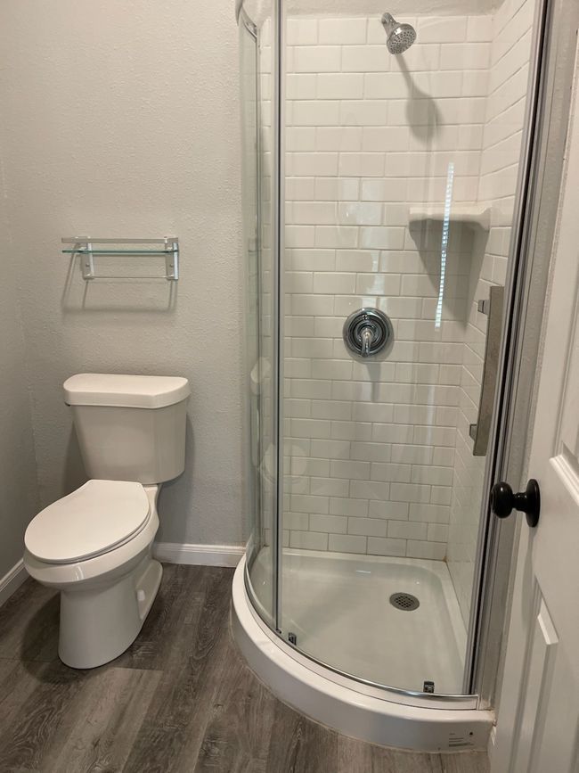 Bathroom with toilet, a shower with shower door, and hardwood / wood-style floors | Image 12