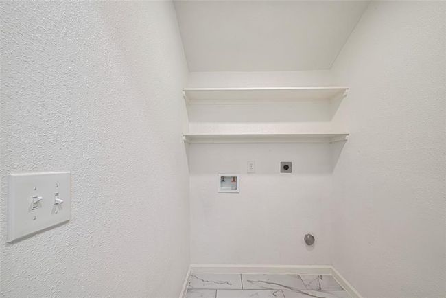 The laundry room provides ample room for side-by-side machines, with built-in shelving above for added utility and storage. | Image 15