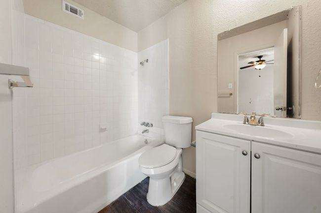 Bathroom featuring toilet, vanity, shower / bathtub combination, wood finished floors, and visible vents | Image 11
