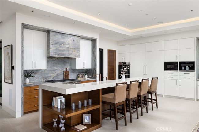 The open-concept, gourmet kitchen impresses with premium Dacor appliances, Miele built-in coffee station, walk-in pantry, and oversized porcelain and quartzite island. | Image 10