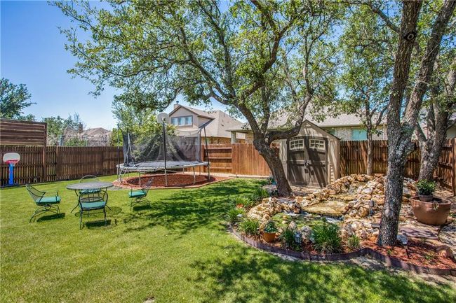 Fenced backyard with a trampoline and a shed | Image 25
