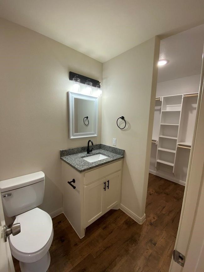 Bathroom featuring wood finished floors, vanity, toilet, and baseboards | Image 11