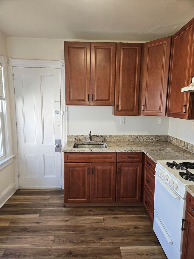 Kitchen featuring a sink, stove, dark wood-type flooring, and ventilation hood | Image 4