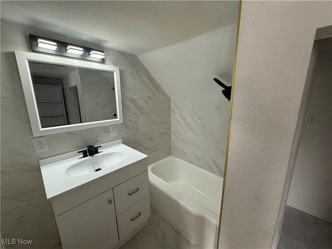 Full bathroom featuring marble finish floor, a textured ceiling, a bath, and vanity | Image 5