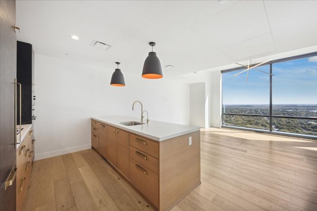 Kitchen featuring a peninsula, light wood finished floors, floor to ceiling windows, modern cabinets, and pendant lighting | Image 6