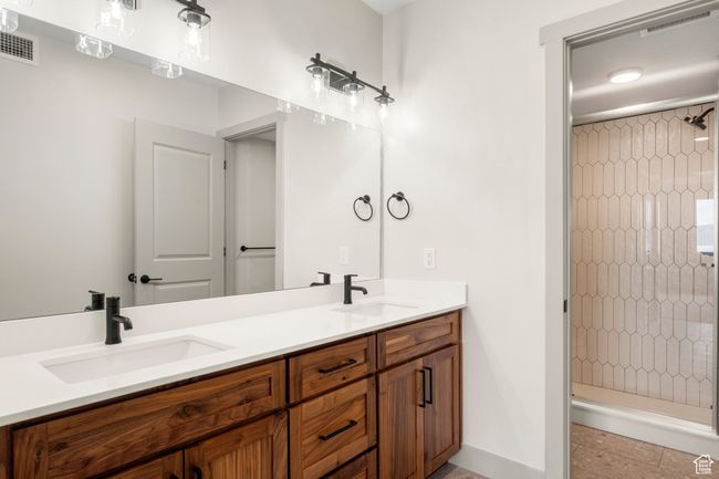 Full bath featuring a shower stall, double vanity, and baseboards | Image 16