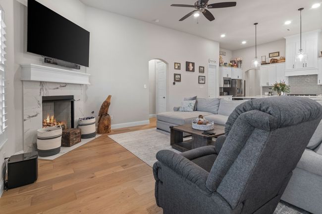 Living room featuring recessed lighting, a fireplace, light wood-style floors, arched walkways, and a ceiling fan | Image 10