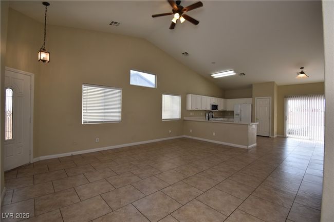 Unfurnished living room with plenty of natural light, a ceiling fan, high vaulted ceiling, and light tile patterned floors | Image 5