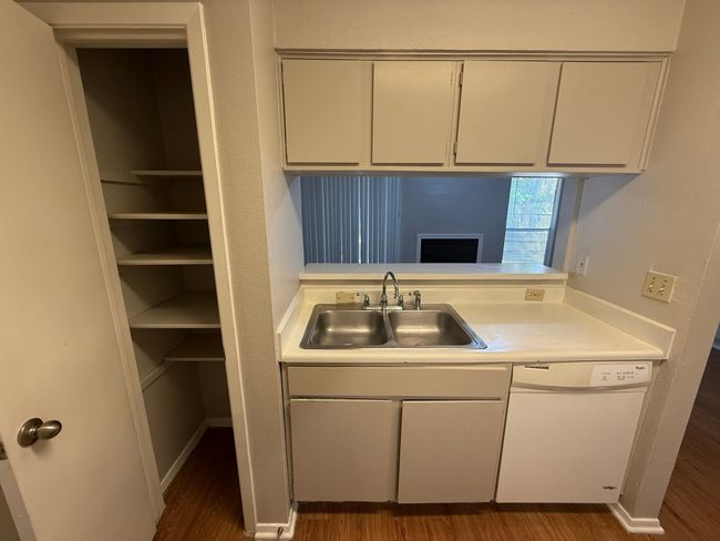 Kitchen with light countertops, wood finished floors, white dishwasher, and white cabinets | Image 8