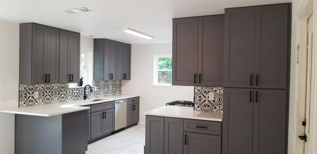 Kitchen with stainless steel dishwasher, a sink, decorative backsplash, light marble finish floors, and light countertops | Image 11