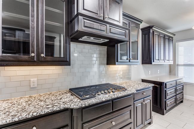 Kitchen featuring custom range hood, dark brown cabinetry, tasteful backsplash, and stainless steel gas stovetop | Image 13