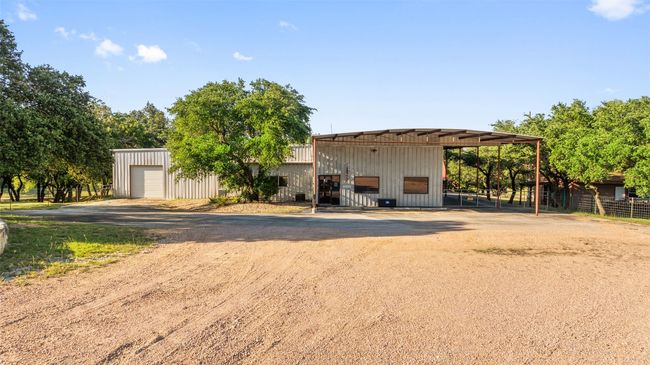 View of front facade featuring an outdoor structure, dirt driveway, board and batten siding, and a detached garage | Image 29