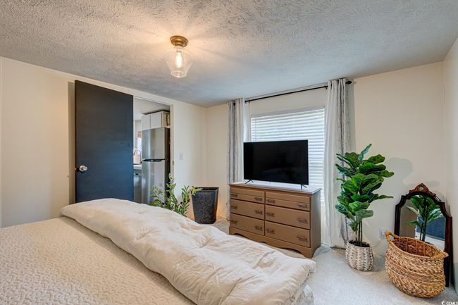 Carpeted bedroom featuring freestanding refrigerator and a textured ceiling | Image 16