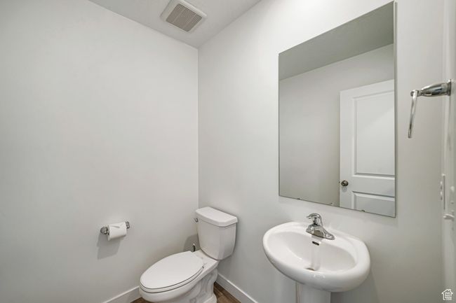Half bathroom featuring a sink, toilet, baseboards, and wood finished floors | Image 17