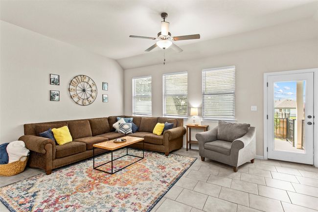 Living area with ceiling fan, plenty of natural light, light tile patterned flooring, and vaulted ceiling | Image 11