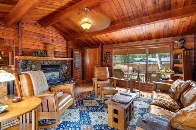 Living area with wood finished floors, wooden walls, wooden ceiling, and a stone fireplace | Image 4